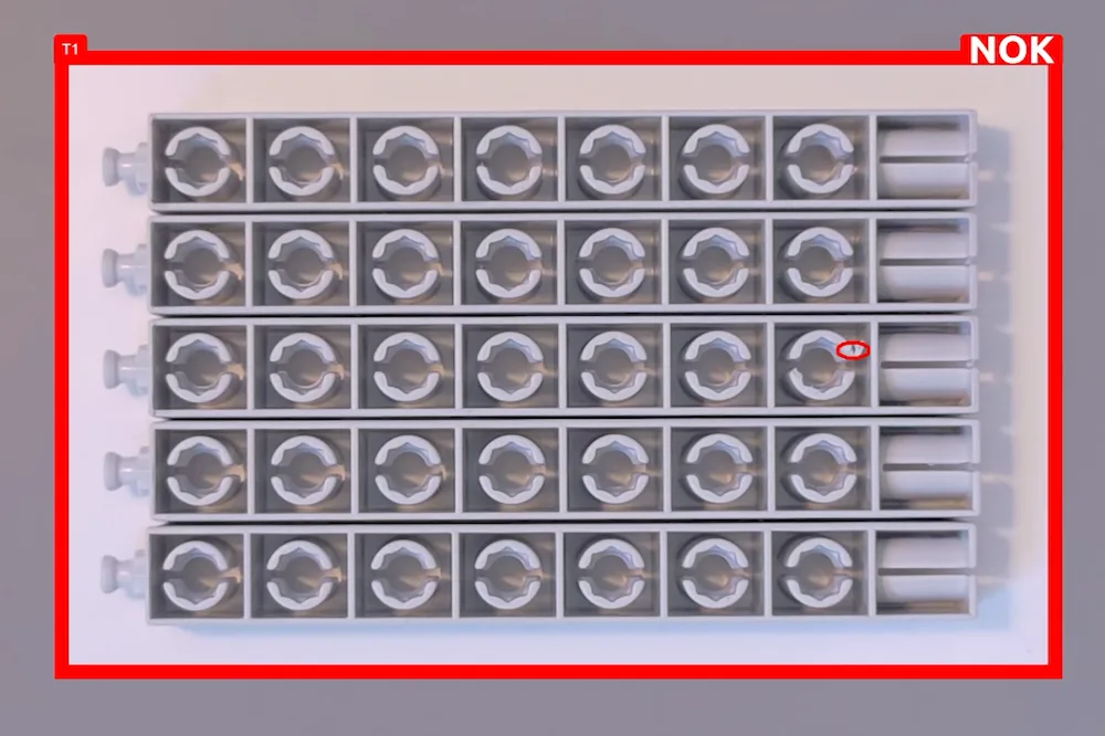 Prüfbild: Tray mit Spritzgussteilen, ein fehlerhaftes Teil ist von der Quality-Box rot markiert